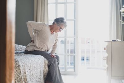 Midsection of man sitting on bed at home