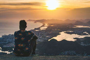 Rear view of person on landscape against sky during sunset