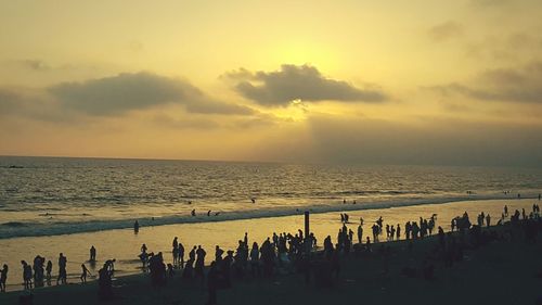 Silhouette people on beach against sky during sunset