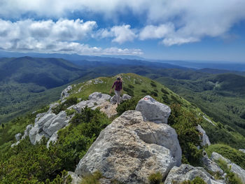 Rear view of man on rock against sky