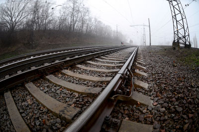 Diminishing perspective of railroad tracks against sky during foggy weather