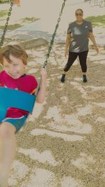 Happy girl playing on swing at beach