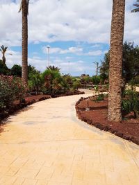 View of empty footpath against cloudy sky