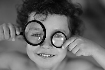 Close-up portrait of smiling boy holding two magnifiers