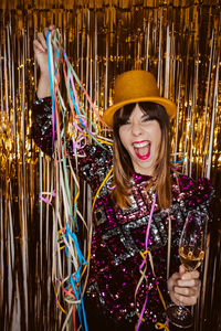 Portrait of smiling young woman wearing hat against golden background