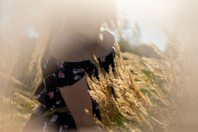 Midsection of young woman standing amidst plants