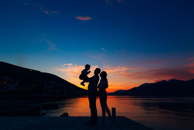 Silhouette couple standing against sky during sunset