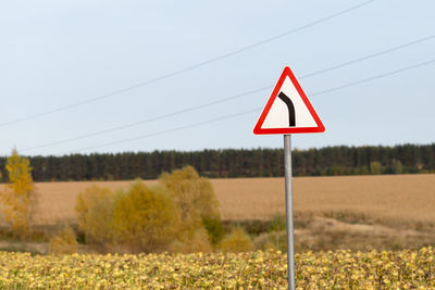 Road sign on field against sky