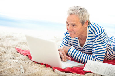 Close-up of man using laptop on beach