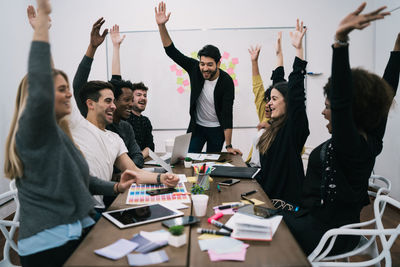 Smiling business person with arms raised enjoying in office