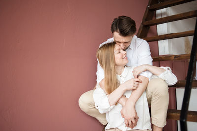 Male and female hugging each other with love sit on stair at home