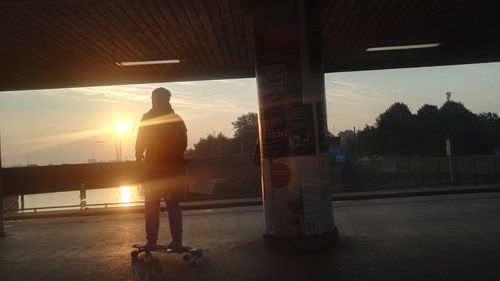 Silhouette man standing by car against sky during sunset