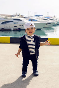 Little boy in a cap standing on the street in the seaport