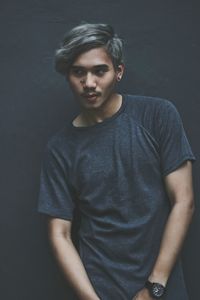 Portrait of young man standing against gray background