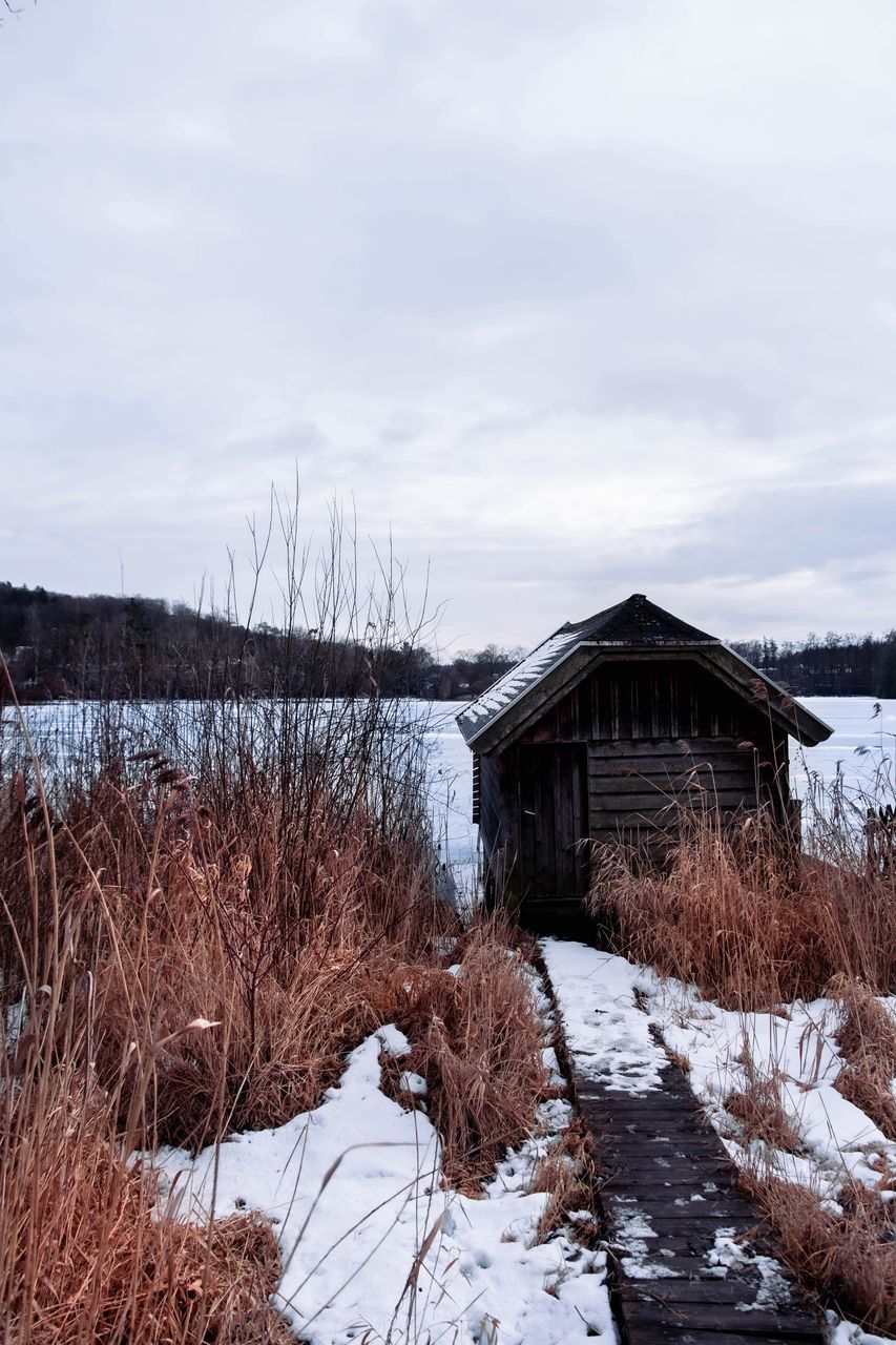 winter, snow, cold temperature, architecture, built structure, sky, cloud, nature, building exterior, house, building, scenics - nature, landscape, no people, plant, environment, water, wood, tree, rural area, day, beauty in nature, land, non-urban scene, tranquility, hut, frozen, rural scene, wilderness, mountain, outdoors, agricultural building, tranquil scene, residential district, freezing, bare tree, barn