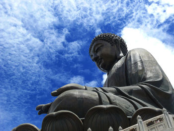 Low angle view of tian tan buddha against cloudy sky