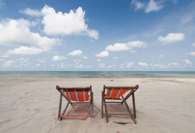 Empty chair on beach against sky