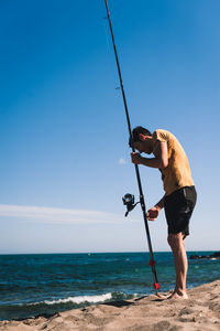 Man holding umbrella on beach against sky