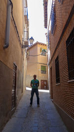 Full length rear view of man walking on footpath amidst buildings