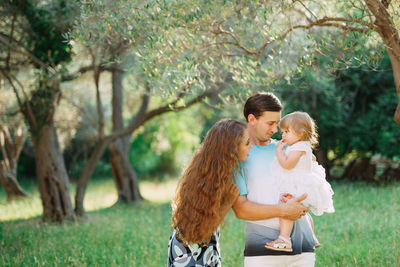 Cute baby with parent against tree