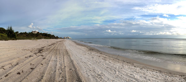 Panoramic sun peeks through the clouds over the ocean at sunset in naples, florida