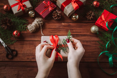 Cropped hands of woman holding christmas decorations on table