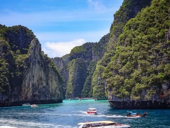 Boats on sea by mountain against sky