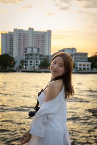 Portrait of young woman standing against sky during sunset