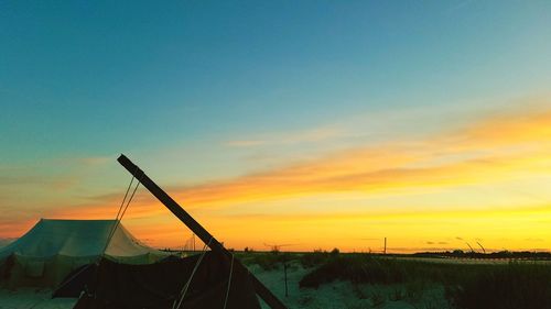 Silhouette sailboats on land against sky during sunset