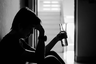 Side view portrait of a young man drinking from window