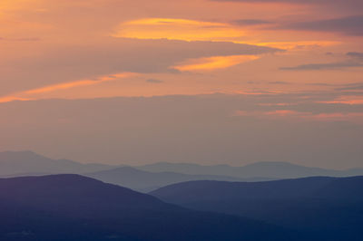 Scenic view of silhouette mountains against orange sky