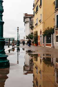 Puddle on sidewalk with reflection of buildings during monsoon