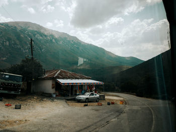 Houses on road by buildings against sky