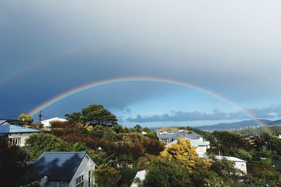 Rainbow over buildings in city against sky