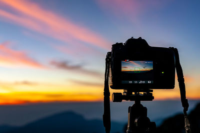 Close-up of camera against sky during sunset