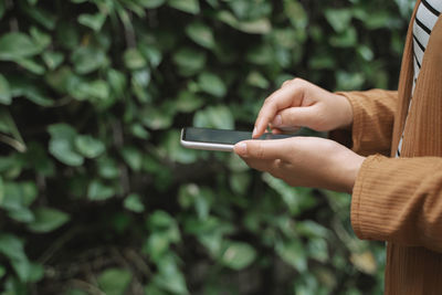 Midsection of man using mobile phone outdoors