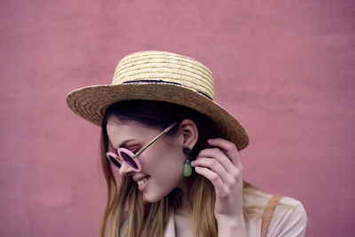 Close-up of smiling woman wearing hat against wall