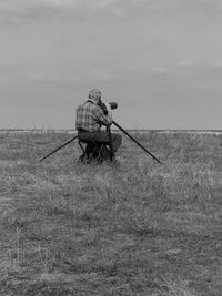 Man photographing on field against sky