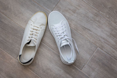 Pair of trendy new and old white shoes on light wooden background, top view