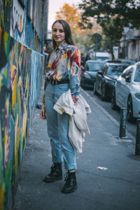 Portrait of teenage girl standing on footpath in city