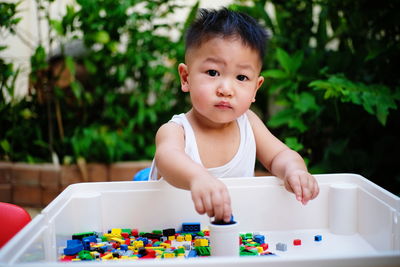 Portrait of cute baby boy playing with toys in yard