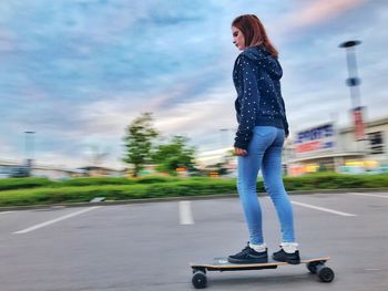Low angle view of woman skateboarding on road