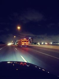 Cars on road seen through car windshield at night