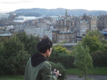 Rear view of man with camera looking at city