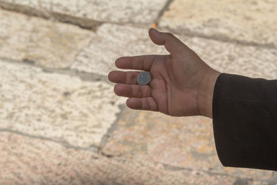 Close-up of man holding coin outdoors