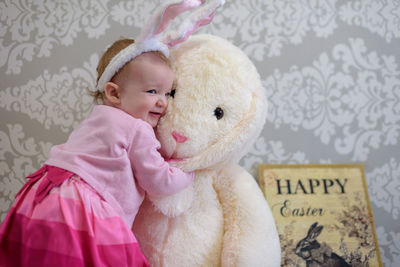 Cute baby girl playing with stuffed toy at home