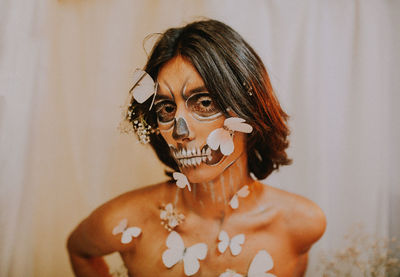 Portrait of shirtless young woman standing against wall