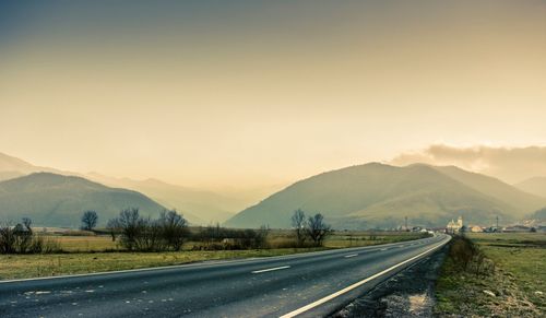 Road by mountains against sky