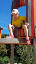 Low angle view of girl on jungle gym at park during sunny day