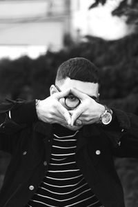 Portrait of teenage boy gesturing while covering face with hands